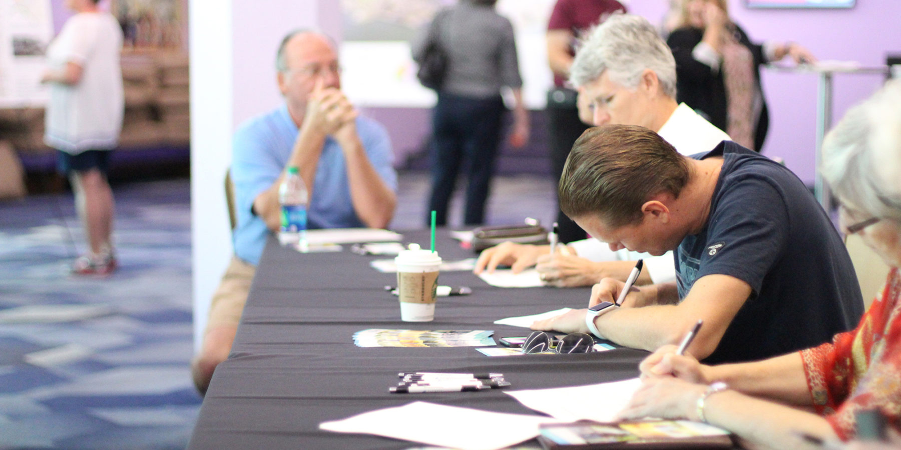 a group sits at a table filling out paperwork