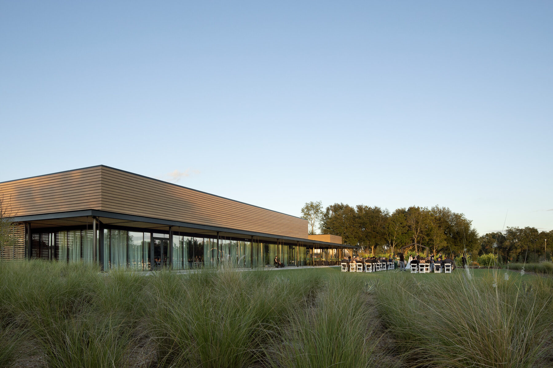 photograph of event center taken from outdoor lawn with wedding reception occuring on lawn