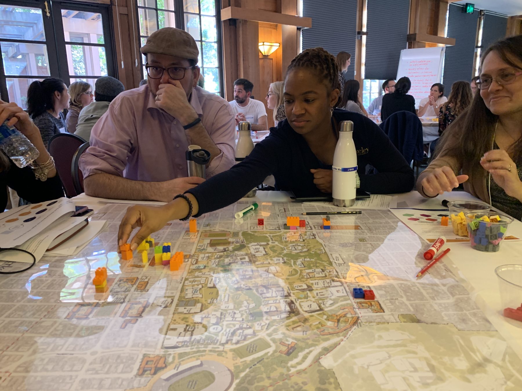 People sitting at a table moving pieces on a large site plan