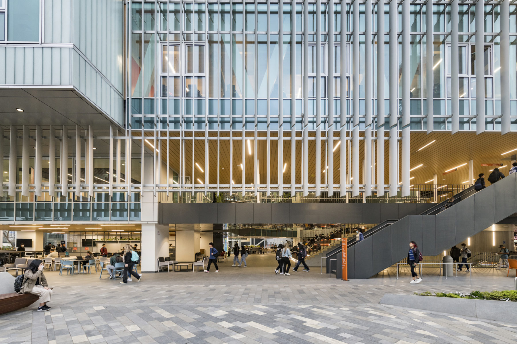 elevational exterior photo of east facade at dusk. students walking around the main circulation stairway